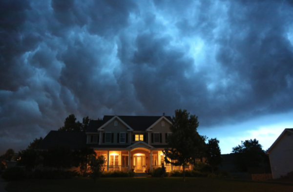 home with porch lights before a storm