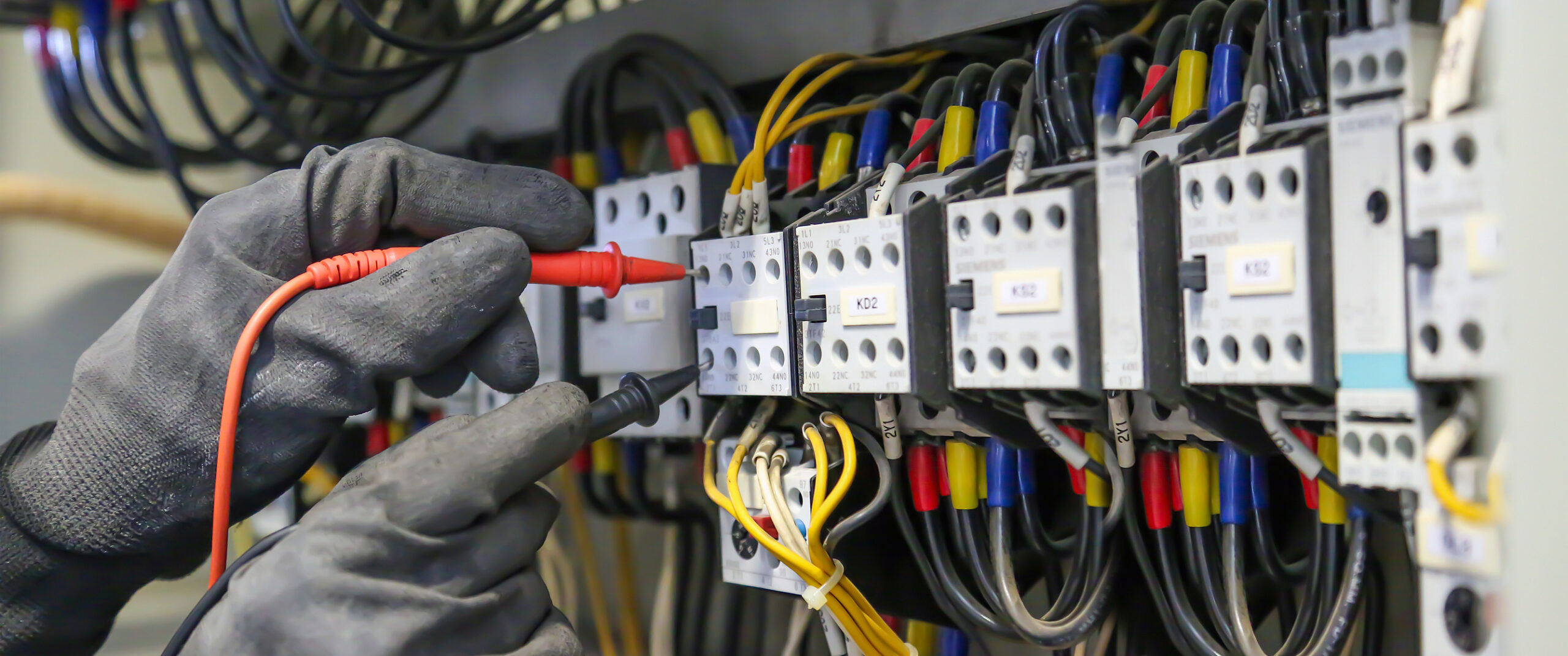 Close-up of electrician's gloved hands rewiring circuit breakers