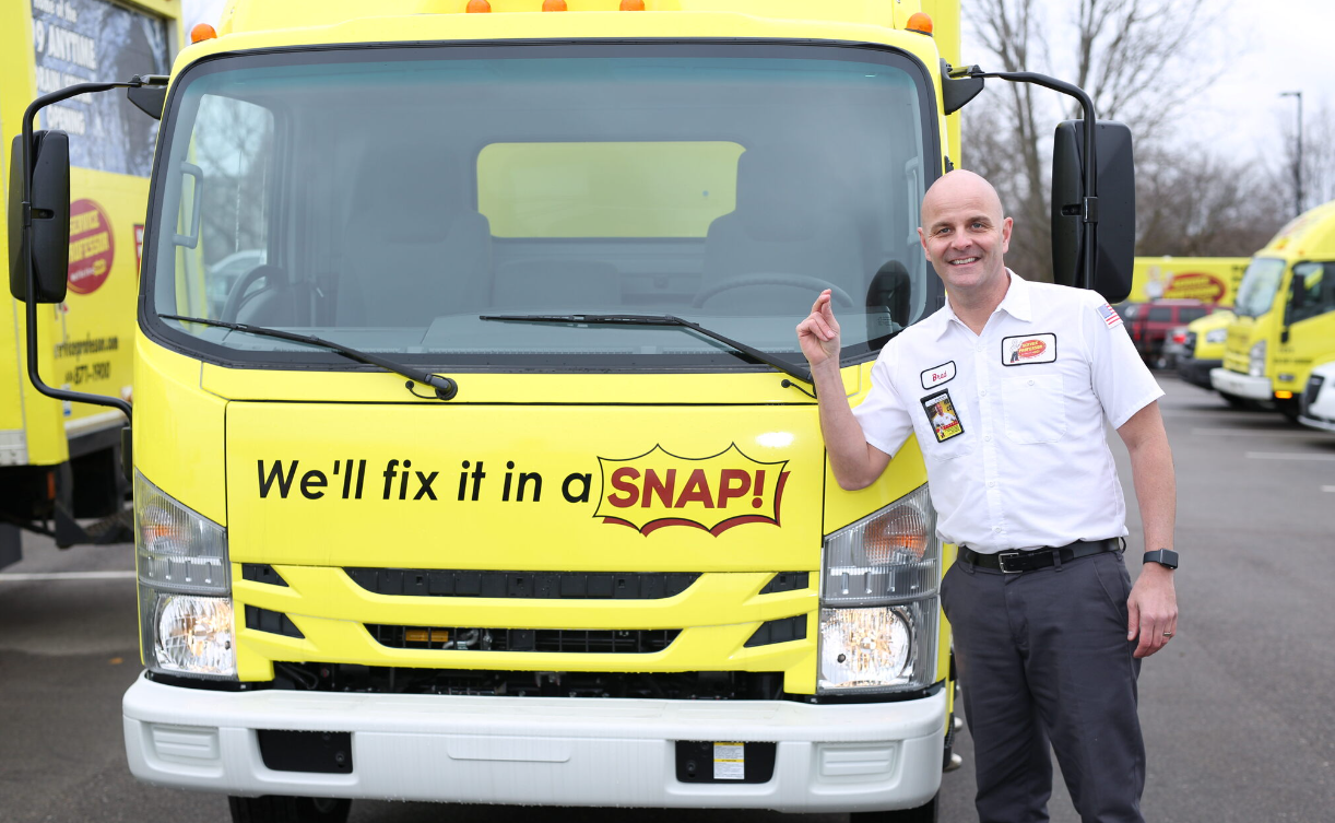 Service Professor technician smiling and standing next to a yellow service truck with slogan on the front.