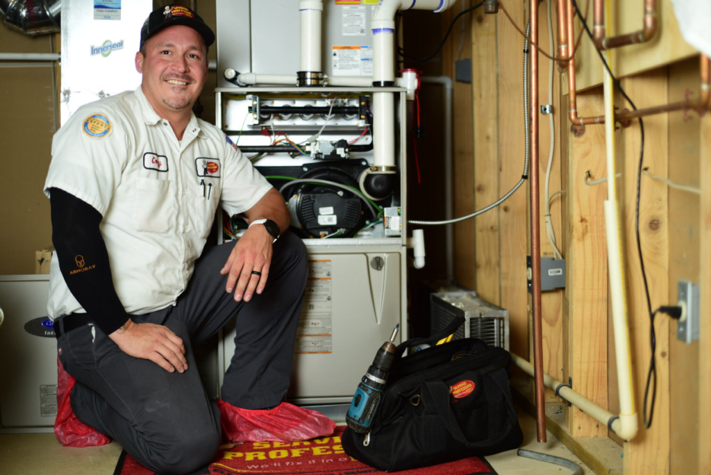 Service Professor HVAC technician smiling next to a new furnace installation.