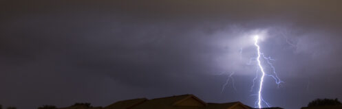 Lightning strikes in the night near family houses