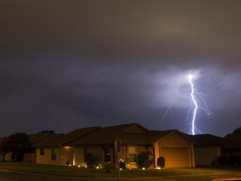Lightning strikes in the night near family houses