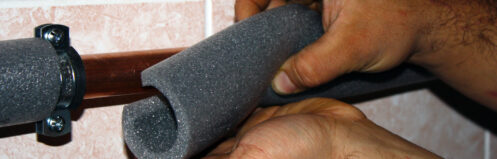 Worker cuts the foam insulation for pipes